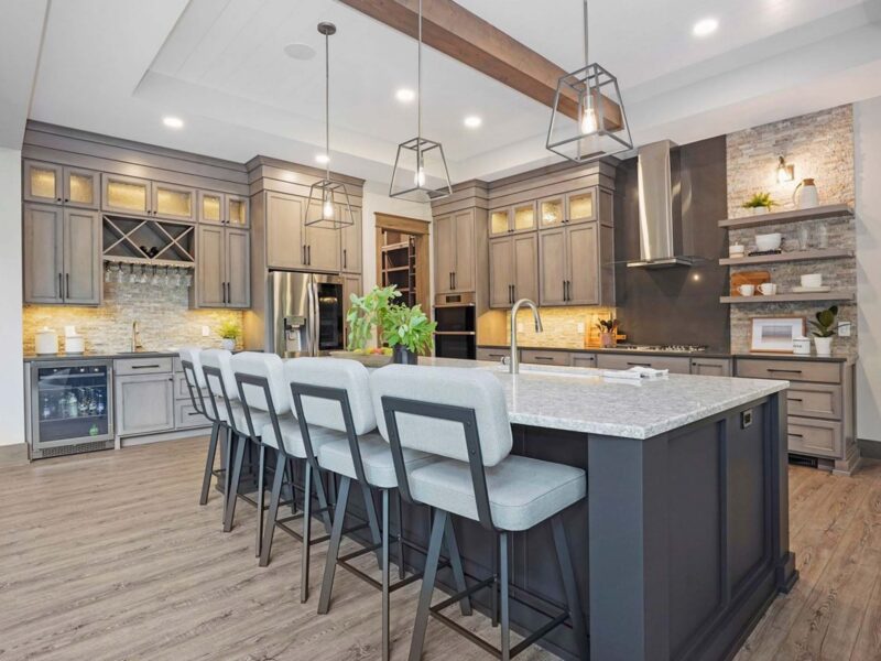 Custom kitchen and dining room area with unique low hanging lamps and stainless steel appliances surrounded by light grey accents