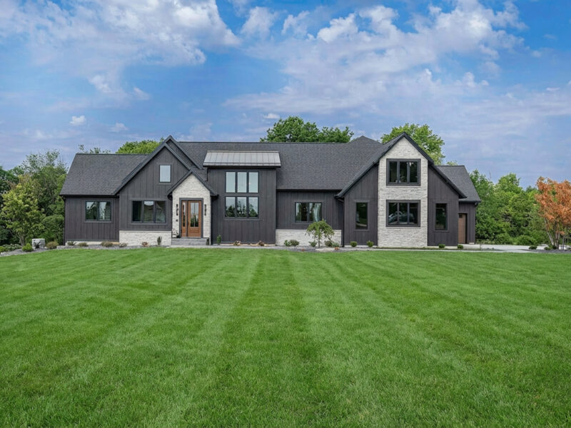 Luxury new black home with a green yard